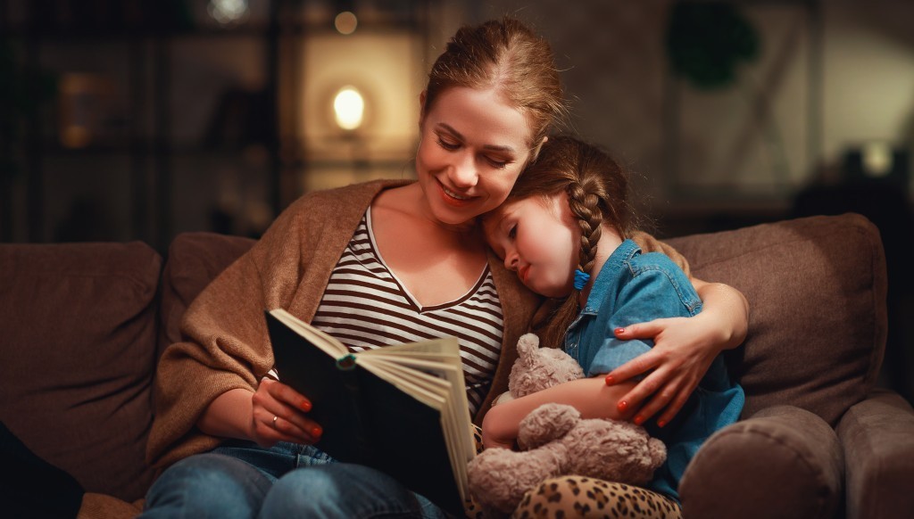 A mother is reading a book to her little child before bedtime.