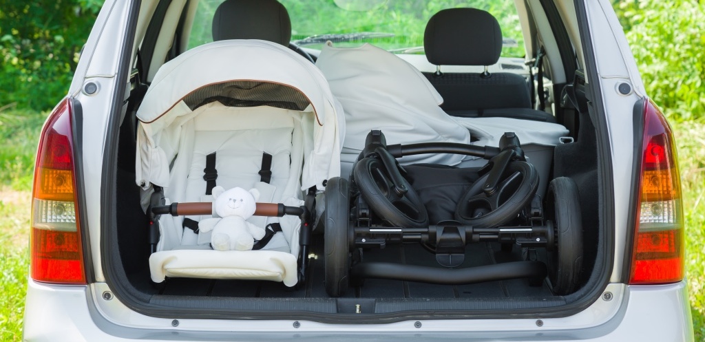 arts of baby carriage in opened car trunk.