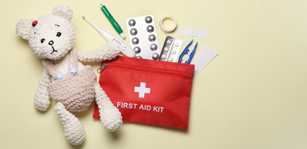 Red first aid kit with medical supplies and a teddy bear on a yellow background