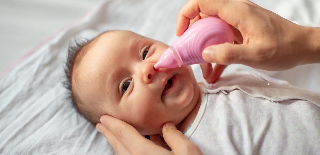 Mother using baby nasal aspirator mucus nose suction