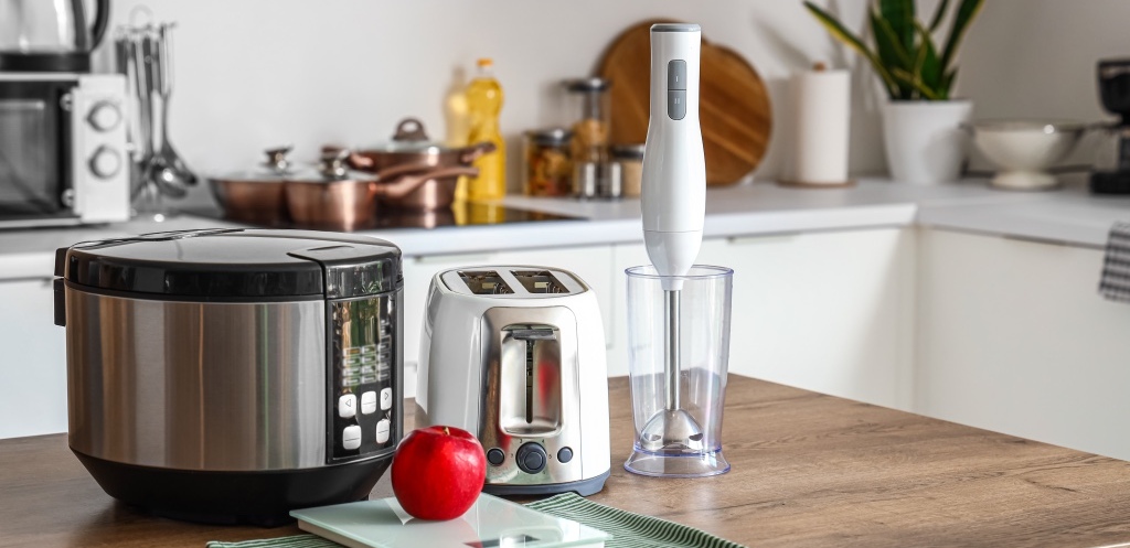 Blender, toaster, multi cooker and apple on wooden table in kitchen