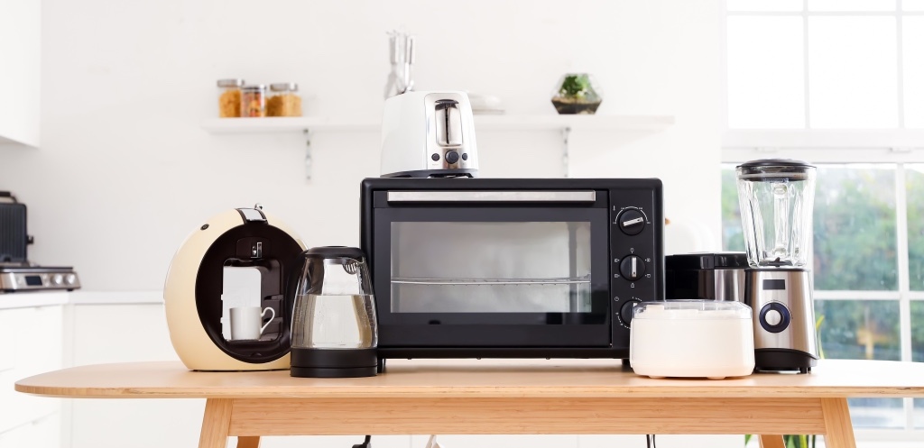 Wooden table with set of modern appliances in light kitchen