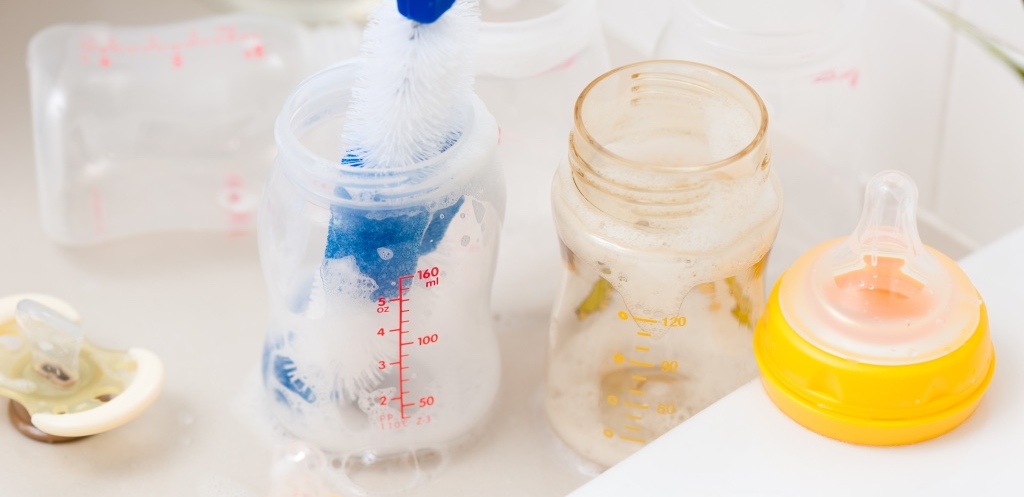 Washing baby bottles and nipples with soft bottle brush and dishwashing liquid